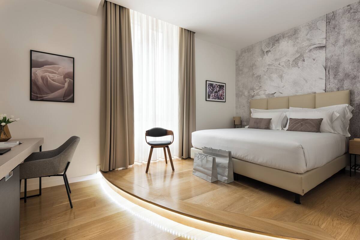 A modern hotel room with a bed, a desk, and a chair.