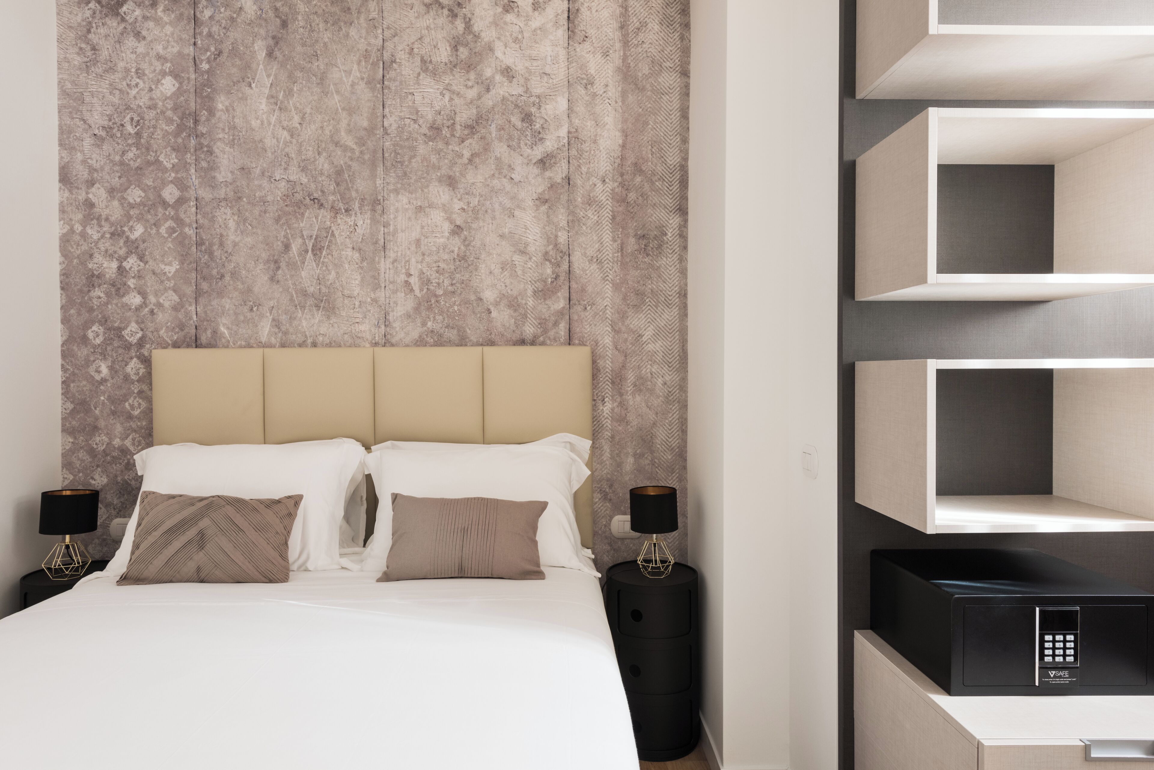 Ein modernes Schlafzimmer mit Bett, Nachttischen und integrierten Regalen.