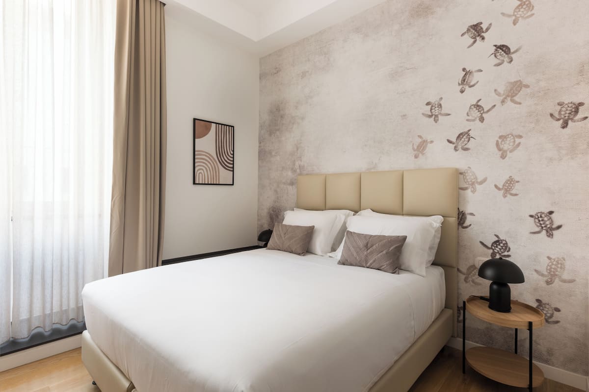 A modern bedroom with a large bed, a headboard, and a wall with a turtle pattern.