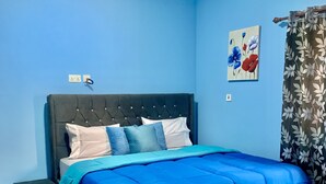 A bedroom with a bed, a nightstand, a bench, and a wall with a floral curtain.