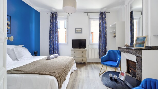 Ein Hotelzimmer mit Bett, Fernseher, Kamin und blauem Sessel.