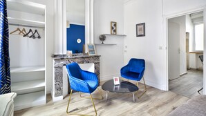 Ein modernes Wohnzimmer mit Marmorfeuerstelle, zwei blauen Sesseln, einem runden Couchtisch und einer blauen Akzentwand.