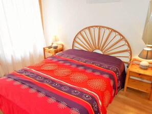 A bedroom with a wooden headboard, two bedside tables with lamps, and a bed with a patterned bedspread.
