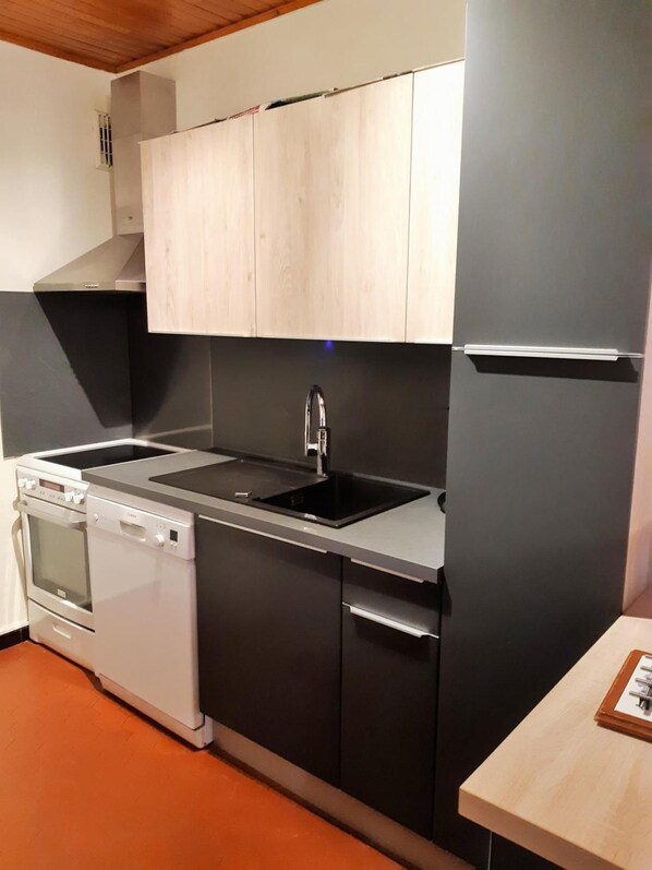 A compact kitchen with a built-in oven, dishwasher, and a double sink.