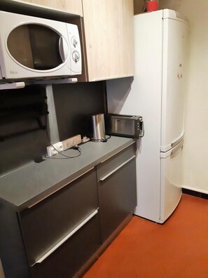 A compact kitchen with a microwave, toaster, and a white refrigerator.