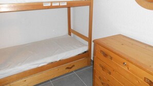 A bunk bed with a wooden frame and a dresser with drawers. - 50m from resort center, 4th floor, view mountain, balcony, parking, tv, ski locker, 30m² (Les Deux Alpes)