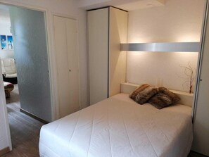 A bedroom with a bed, a bedside table, a lamp, and a wardrobe.