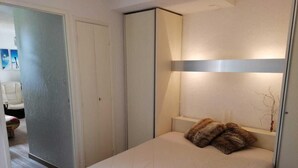 A bedroom with a bed, a bedside table, a lamp, and a wardrobe. - 50m from resort center, Ground floor, view ski slopes, balcony, parking, tv, ski locker, 30m² (Les Deux Alpes)