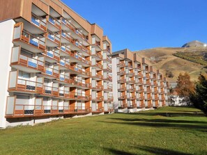 A multi-story hotel with balconies, a flat roof, and a grassy area in front. - 50m from ski slopes, Ground floor, view ski slopes, balcony, parking, tv, ski locker, 30m² (Les Deux Alpes)