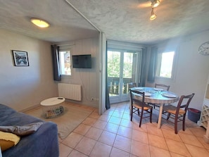 Una habitación con una mesa de comedor, sillas, un sofá, un televisor y un ventanal con vistas.