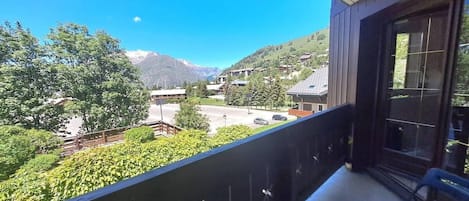 Un balcón con vista a un paisaje montañoso, una silla y una ventana.