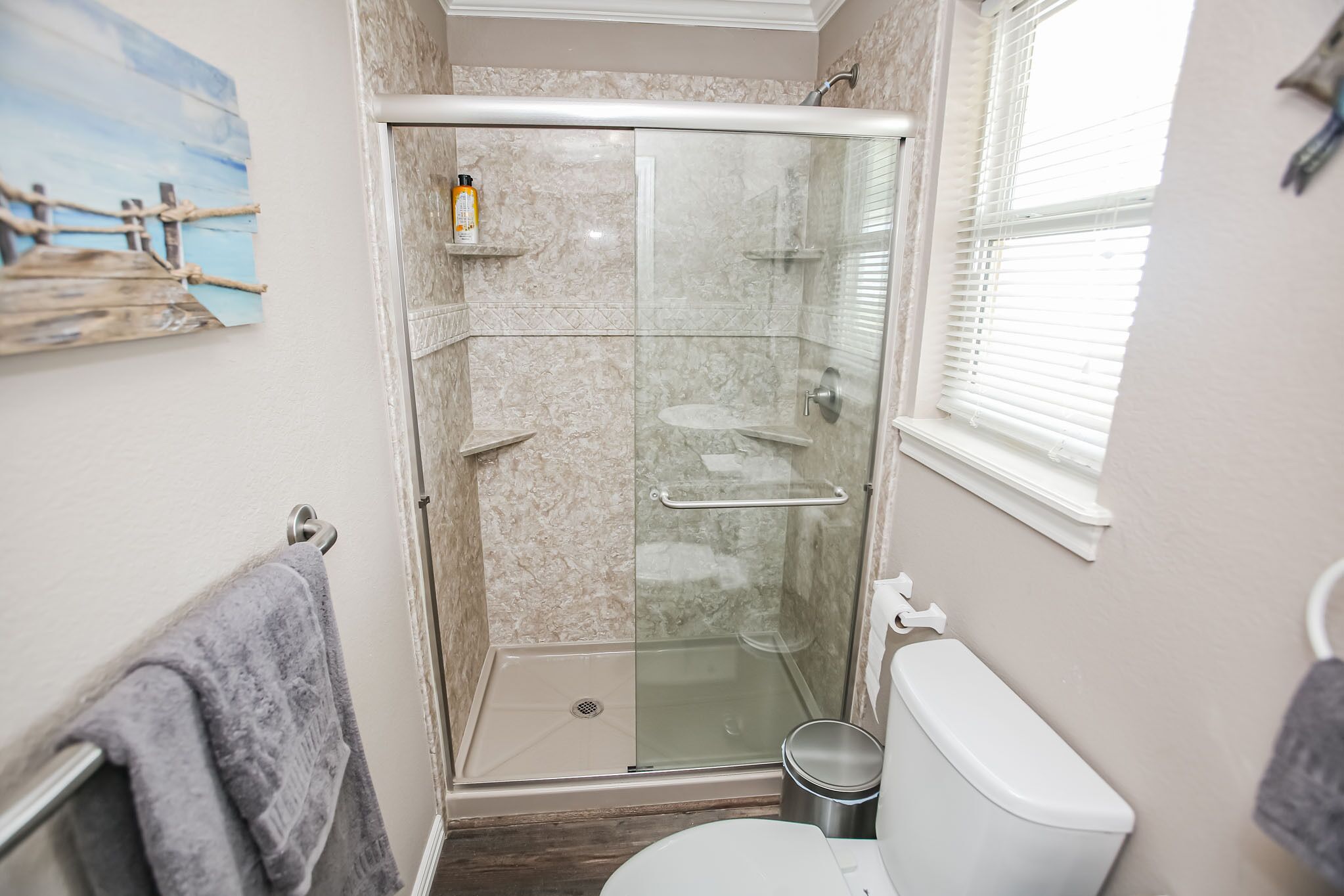 A bathroom with a glass-enclosed shower, a toilet, and a towel rack.