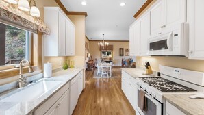 A kitchen with white cabinets, a stainless steel sink, a microwave, and a stove. - Relaxed Retreat with Premiere Location and Views, Only 6 Steps to Get In, Garage (Whittier)