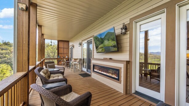 A covered deck with wicker furniture, a fireplace, and a TV mounted on the wall. - Relaxed Retreat with Premiere Location and Views, Only 6 Steps to Get In, Garage (Whittier)