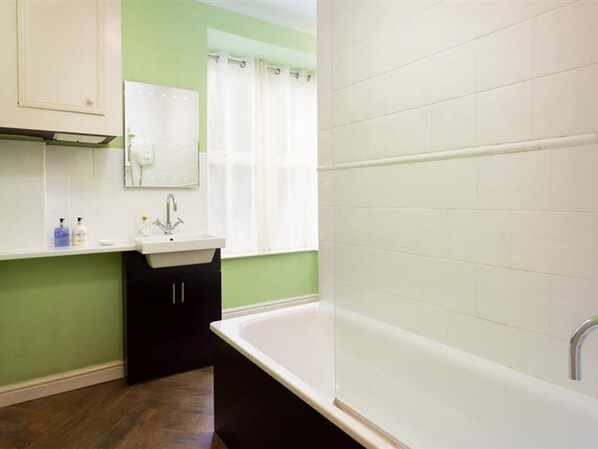 Un baño con una bañera blanca, un lavamanos y un espejo.