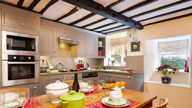 Una cocina moderna con electrodomésticos integrados, una mesa de comedor lista para cuatro personas y una ventana con vistas a zonas verdes.