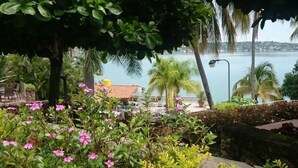 A garden with pink flowers and a view of a body of water and buildings in the distance. - Incredibly Beautiful Big Villa For Up To 32 Guests (Tequesquitengo)