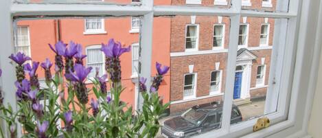 A window with a view of a red brick building and a parked car outside.