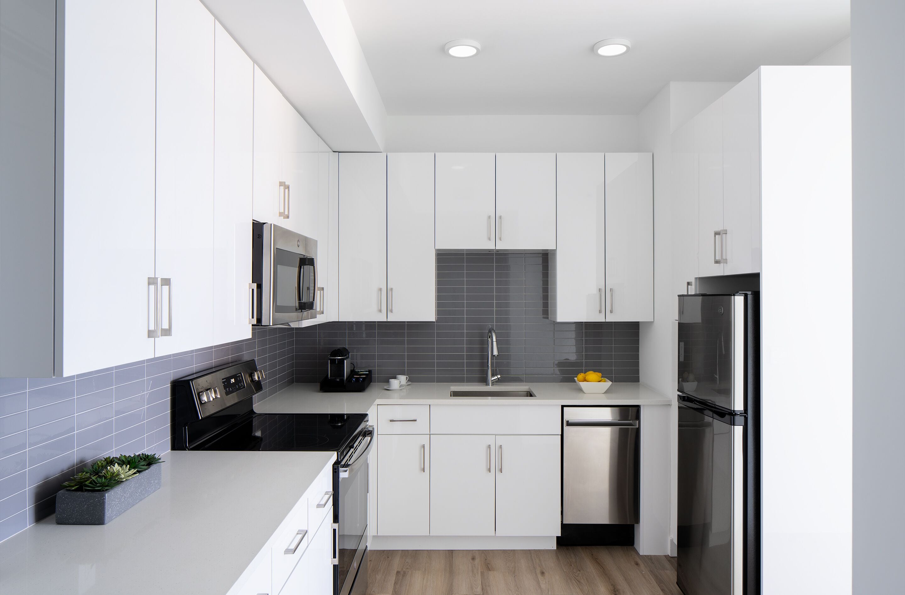 Una cocina moderna con armarios blancos, un refrigerador de acero inoxidable y un horno empotrado.