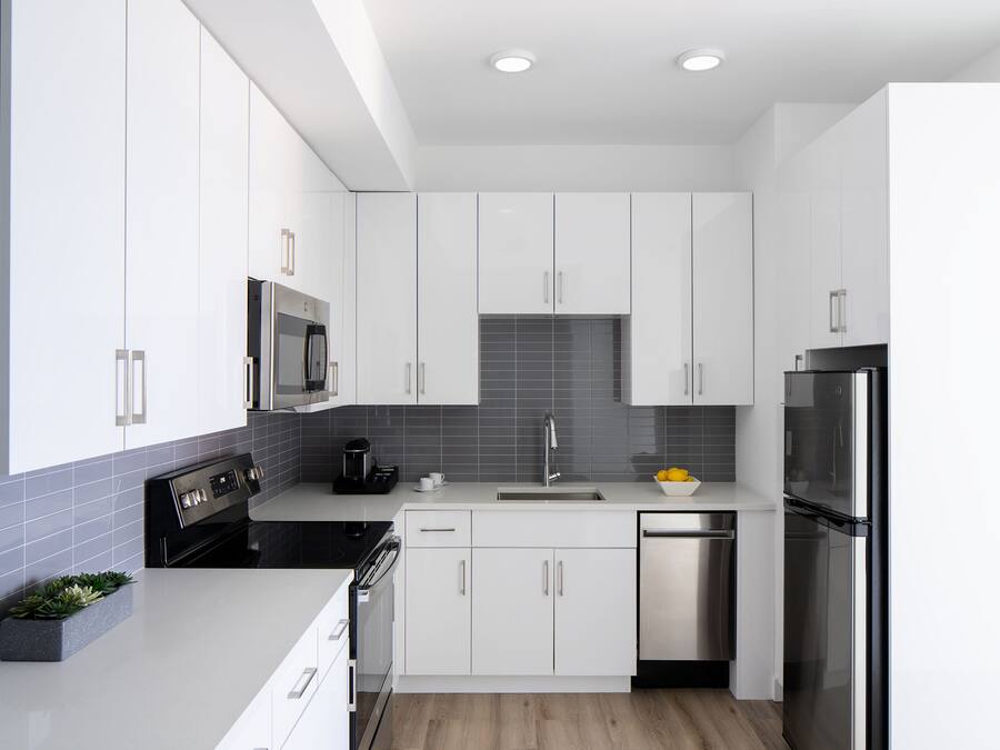 Una cocina moderna con armarios blancos, un refrigerador de acero inoxidable y un horno empotrado.