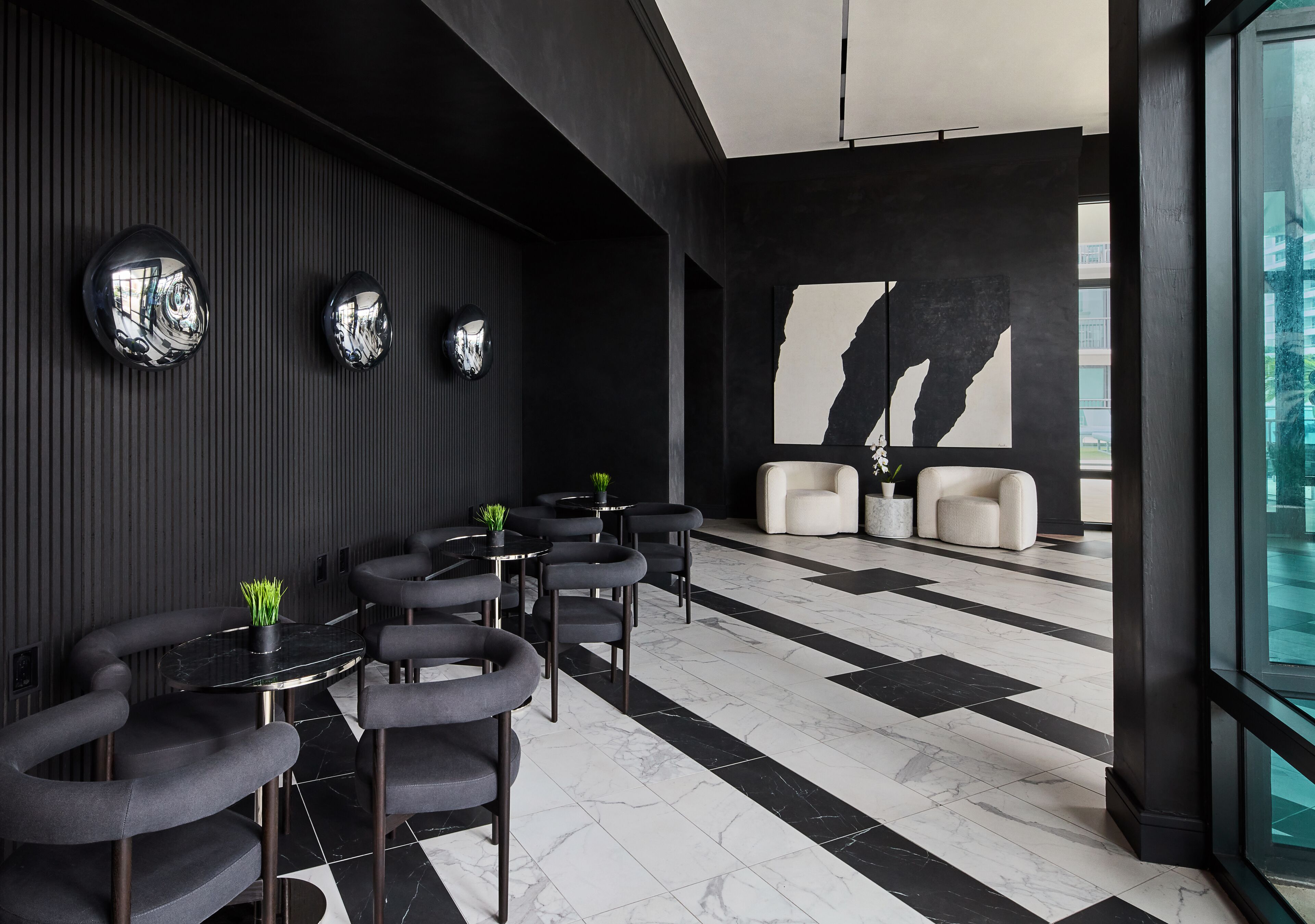 A modern interior with black and white tiled floors, round tables with chairs, and a large window with a view of a building.
