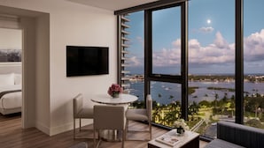 Ein modernes Hotelzimmer mit großem Fenster und Blick auf das Meer und Boote.