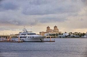 Un yate grande amarrado en un puerto deportivo con un edificio histórico al fondo.