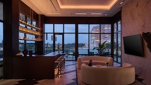 Eine moderne Bar mit einer hohen Bar, Sitzgelegenheiten und einem großen Fenster mit Blick auf die Stadt.
