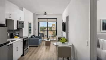 Un appartement moderne doté d’une cuisine, d’un coin repas et d’un balcon offrant une vue sur un immeuble.