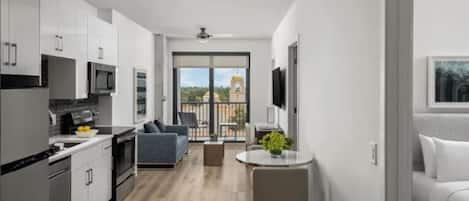 A modern apartment with a kitchen, dining area, and balcony with a view of a building.