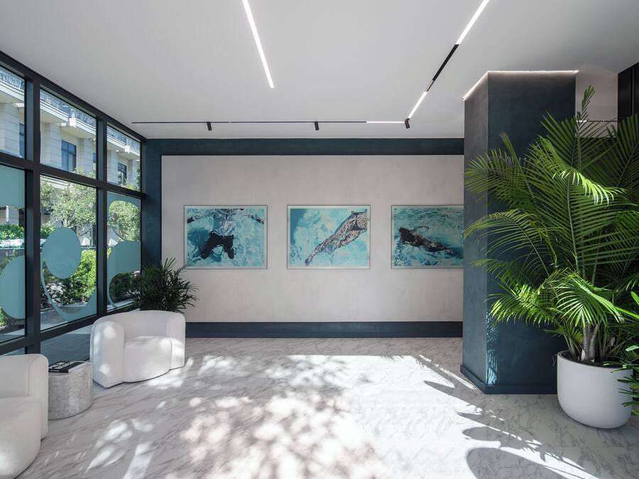 A modern interior with large windows, artwork on the walls, and indoor plants.