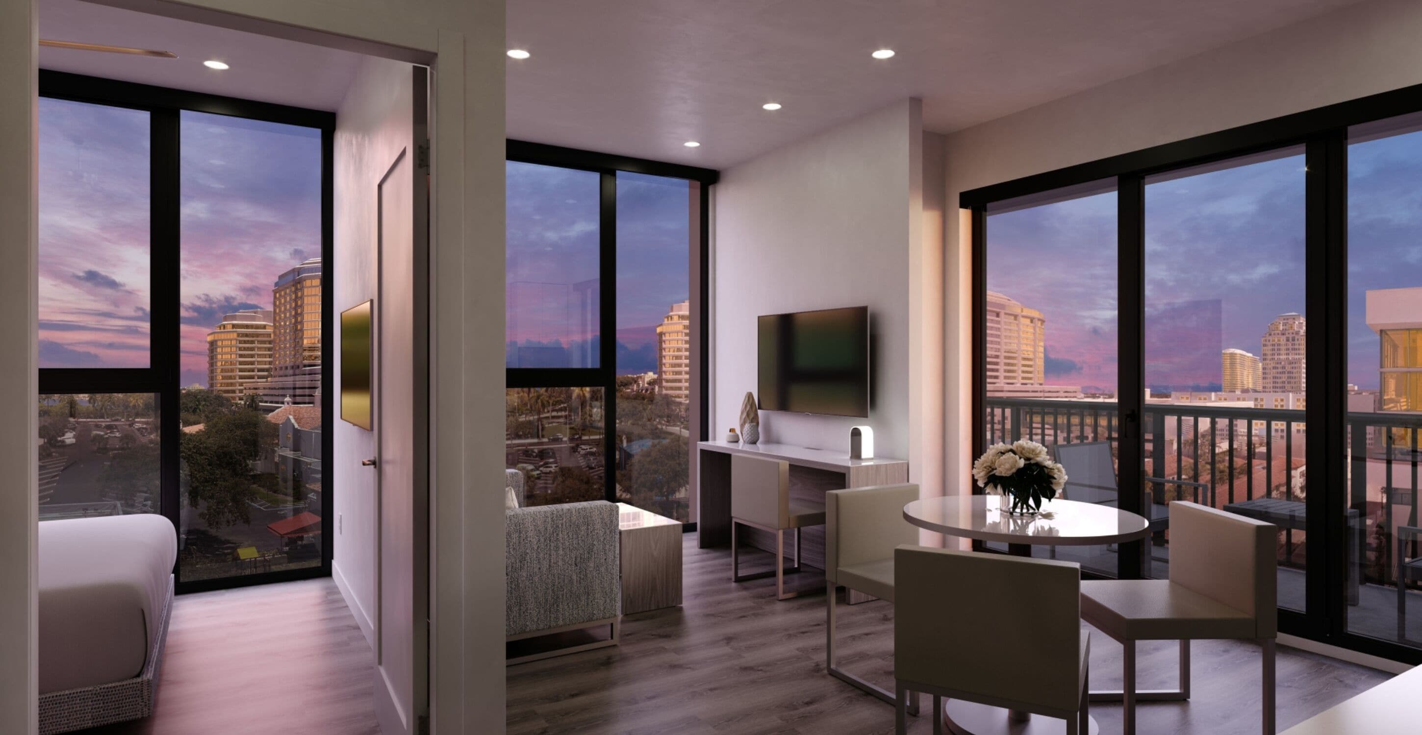 Une chambre d’hôtel moderne dotée de grandes fenêtres, d’un téléviseur à écran plat, d’un coin repas et d’un balcon offrant une vue sur la ville.