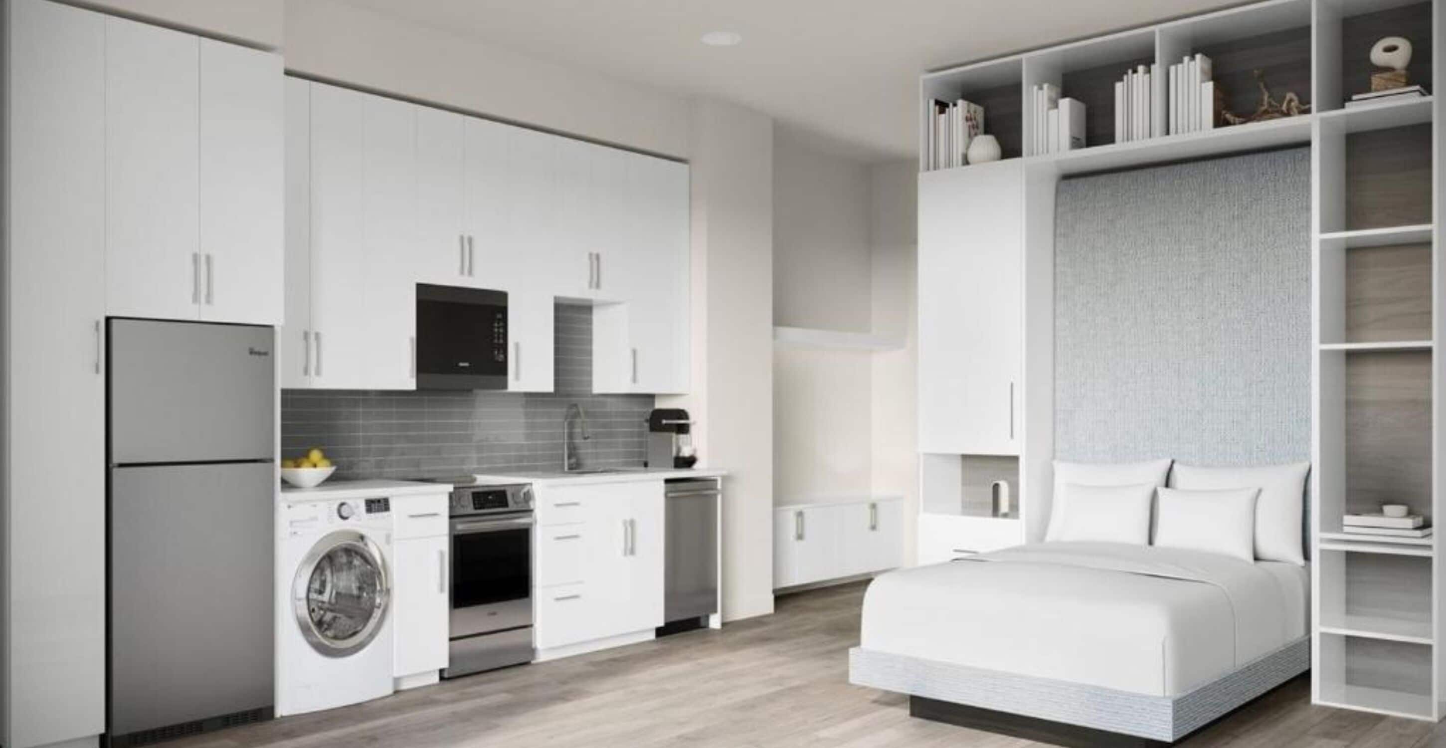 A modern, compact bedroom with a bed, a built-in wardrobe, and a kitchenette with a washing machine and oven.