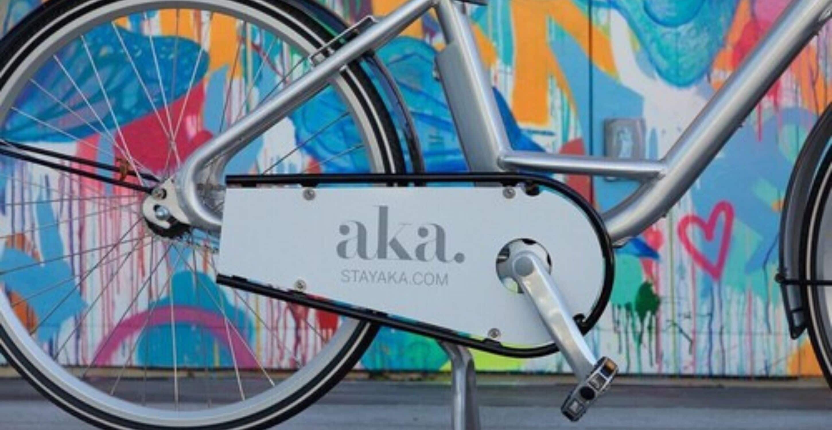 A stationary bike with a white frame and a heart symbol, parked against a colorful graffiti wall.