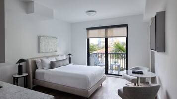 Une chambre d’hôtel moderne équipée d’un lit, d’une petite table, d’une chaise et d’un balcon avec du mobilier d’extérieur.