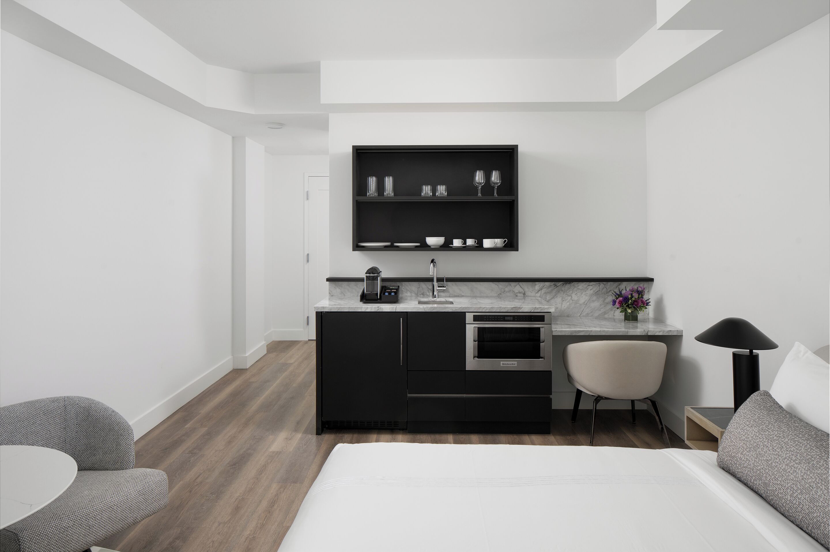 Une chambre d’hôtel moderne équipée d’une kitchenette, d’un lit, d’un bureau et d’une chaise.