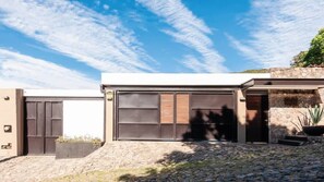 A modern house with a garage, stone wall, and a clear blue sky.