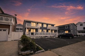 A two-story residential building with a front porch and a parking lot.