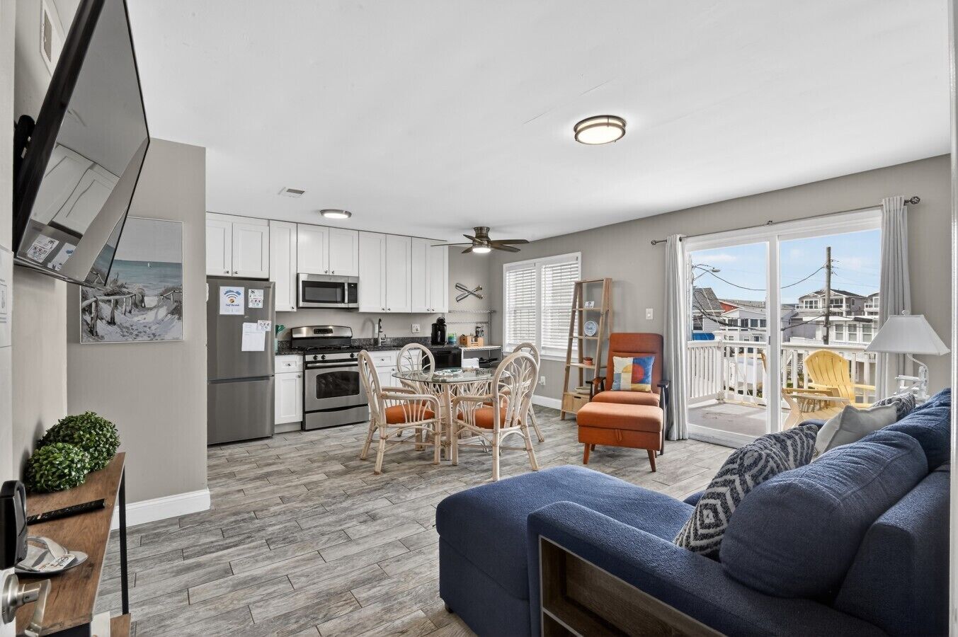 A modern kitchen with white cabinets, stainless steel appliances, and a dining area with wicker chairs.