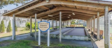 A covered outdoor area with a sign for Dominic R. Costello Brigantine Bocce Courts.