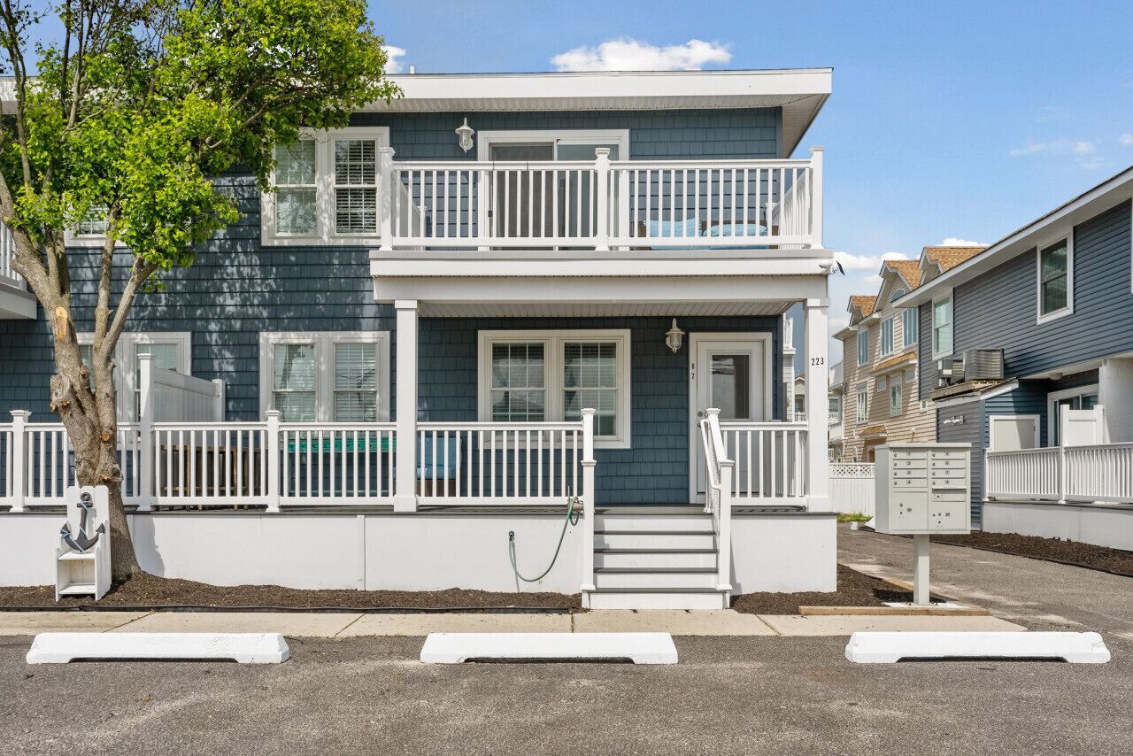 A two-story house with a balcony, white railings, and a front door.