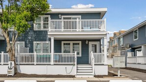 A two-story house with a balcony, white railings, and a front door.