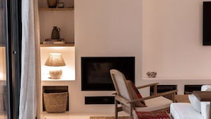 Ein modernes Wohnzimmer mit Kamin, einer Couch, einem Sessel und einem an der Wand befestigten Fernseher.
