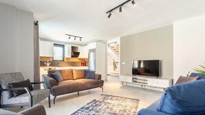 Un salon moderne avec un canapé, un téléviseur et une cuisine en arrière-plan.