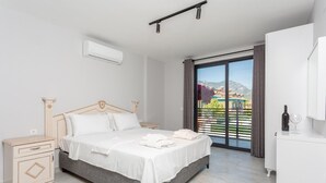 Une chambre moderne avec un lit, des tables de chevet, une armoire et un balcon offrant une vue agréable.