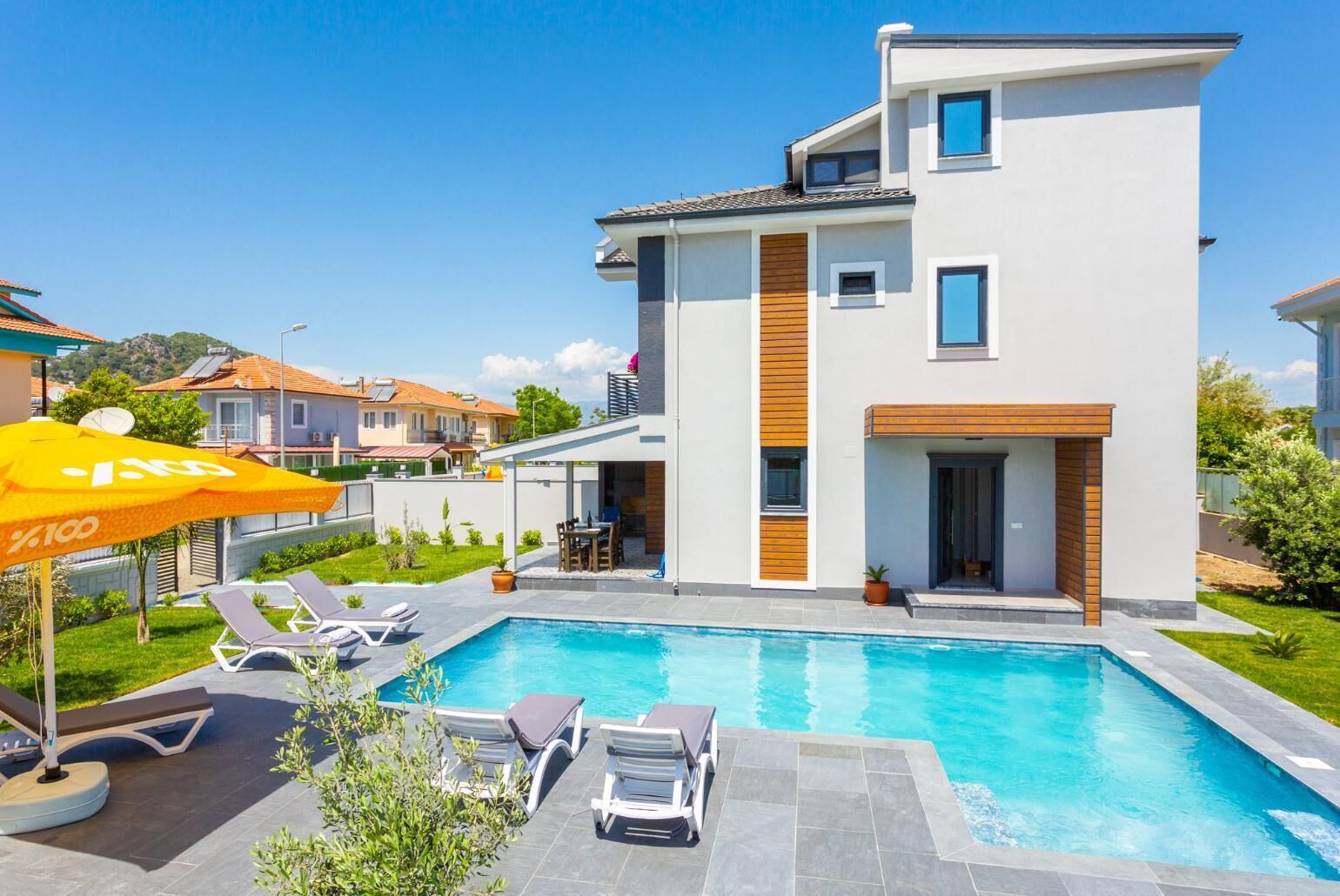 Une maison moderne à deux étages dotée d’une piscine, d’un espace salon extérieur et d’un patio.