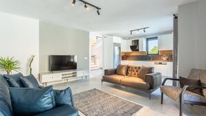 Een moderne woonkamer met een flatscreen televisie, een bank en een kamerbreed tapijt met dessin.