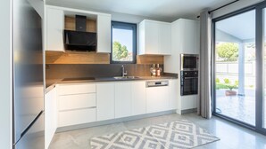 Een moderne keuken met witte kasten, een ingebouwde magnetron en een groot raam.