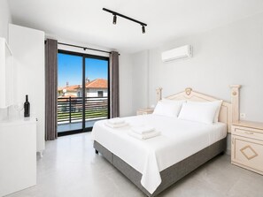 A bedroom with a bed, bedside tables, a wardrobe, a window with curtains, and an air conditioning unit.