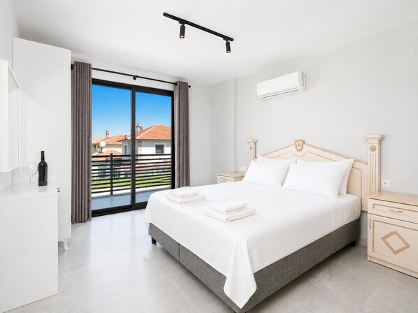 Une chambre à coucher comprenant un lit, des tables de chevet, une armoire, une fenêtre avec des rideaux et un appareil de climatisation.